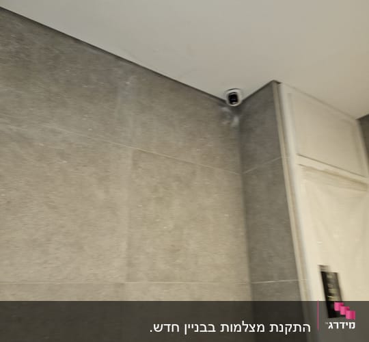 מצלמת אבטחה מותקנת בפינת תקרה על קיר אפור